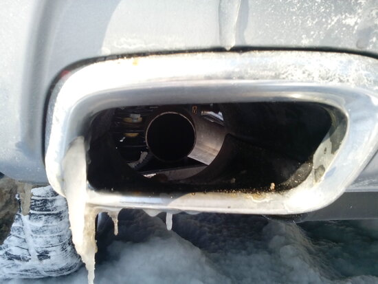 Ржавчина на декоративной рамке выхлопной трубы Джили Атлас (слева)